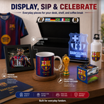 A Barcelona FC merchandise display set on a wooden table, featuring a framed photo print, a ceramic mug, a glowing acrylic Barcelona crest sign, a white water bottle, a trophy keychain, a small collectible box, and a soccer jersey hanging in the background. Text overlays describe each item, with a red banner at the bottom highlighting premium quality and everyday fandom appeal.