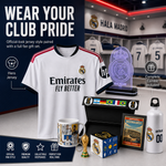 A Real Madrid fan gift set displayed on a dark studio background, including an official white jersey with red and navy trim, a holographic LED light, a collectible keepake box, a mug, a small trophy, a framed print, and a white water bottle. Text highlights key features such as 'Wear Your Club Pride' and 'Official-look jersey style paired with a full fan gift set.
