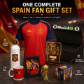 A Spain soccer fan gift set displayed on a dark tabletop with a red-and-navy jersey as the main item, plus a white water bottle, red mug, framed photo, illuminated Spain plaque, small trophy, club cube box, and black gift box. Large text at the top reads 'ONE COMPLETE SPAIN FAN GIFT SET' with callout labels for jersey, custom sipper, gift box + collectibles, mug, and club cube.