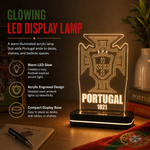 A glowing LED display lamp shaped like the Portugal football crest, shown lit on a wooden surface with promotional text and decor in the background.