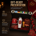 Arsenal-themed gift set presented in a black box with red lining, including a red football mug, white water bottle, glass, keychain, and small trophy replica, with promotional text and Arsenal branding around it.