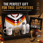 A Germany soccer-themed collector gift set displayed in an open black box on a wooden surface. The set includes a white jersey with black and gold trim, a white mug with the number 11, a gold trophy replica, two white bottles, a framed photo, and a small box.