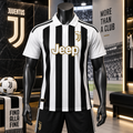 A black and white striped Juventus soccer jersey with a gold Jeep logo is displayed on a black mannequin in a themed retail setting. The mannequin is also wearing black shorts, and the background features Juventus branding, a soccer ball, and a scarf.