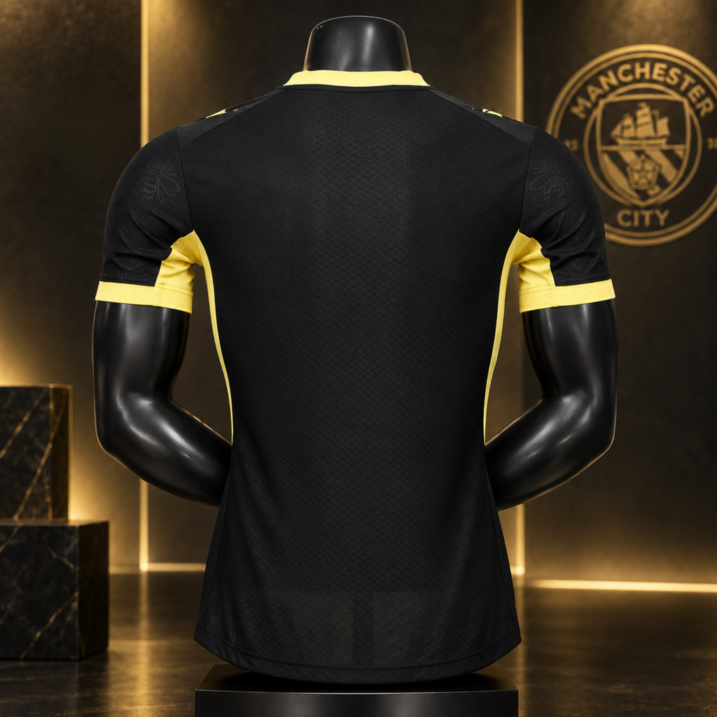 Black short-sleeve Manchester City soccer jersey shown from the back on a black mannequin, with yellow trim at the collar and sleeve cuffs. The Manchester City crest is visible on the background wall.