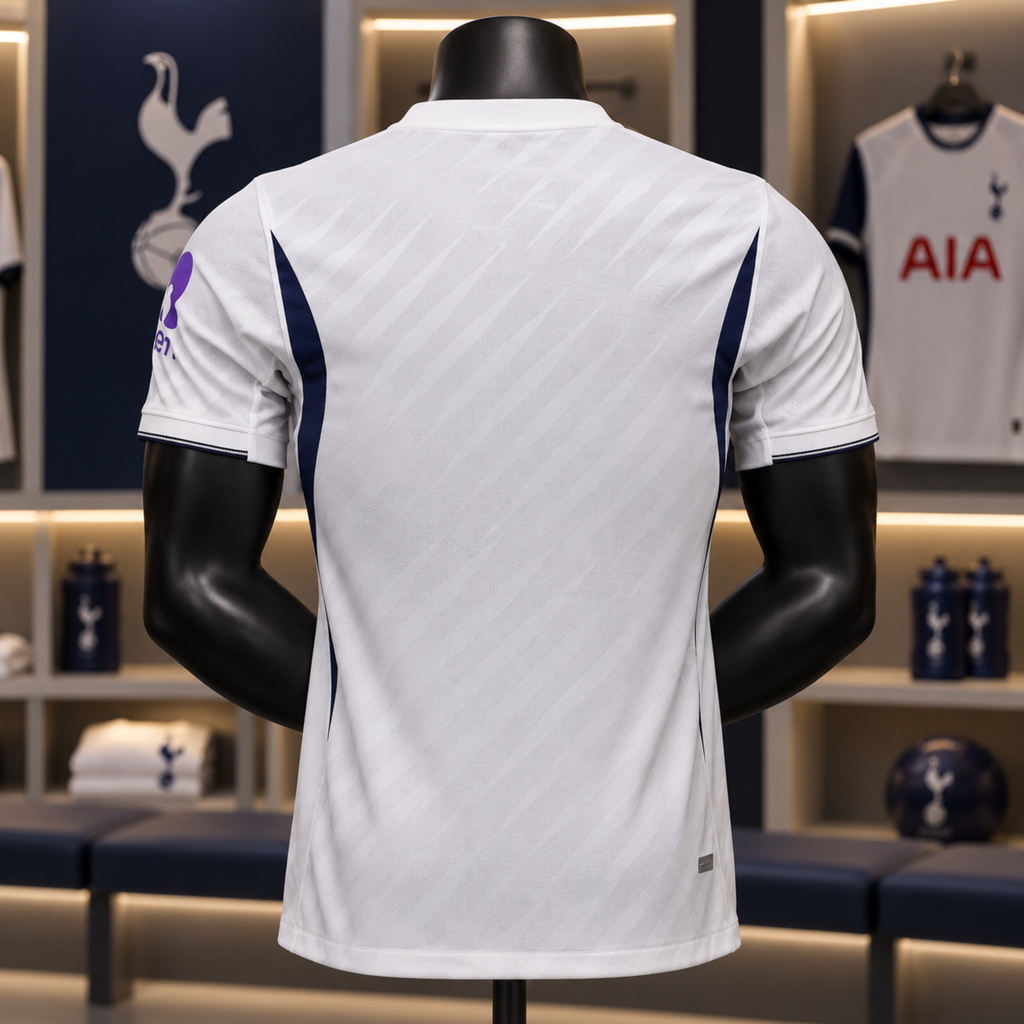 White Tottenham Hotspur football jersey shown from the back on a black mannequin, with navy side panels and a purple crest on the sleeve, set in a locker room display.