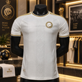 A white short-sleeve soccer jersey with gold trim and a circular Nassr crest on the chest, displayed on a black mannequin torso inside a retail store.