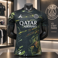 A Paris Saint-Germain soccer jersey displayed on a black mannequin torso inside a retail store. The jersey features a dark green and black marbled pattern with white printed logos for Jordan, Qatar Airways, and Paris Saint-Germain.